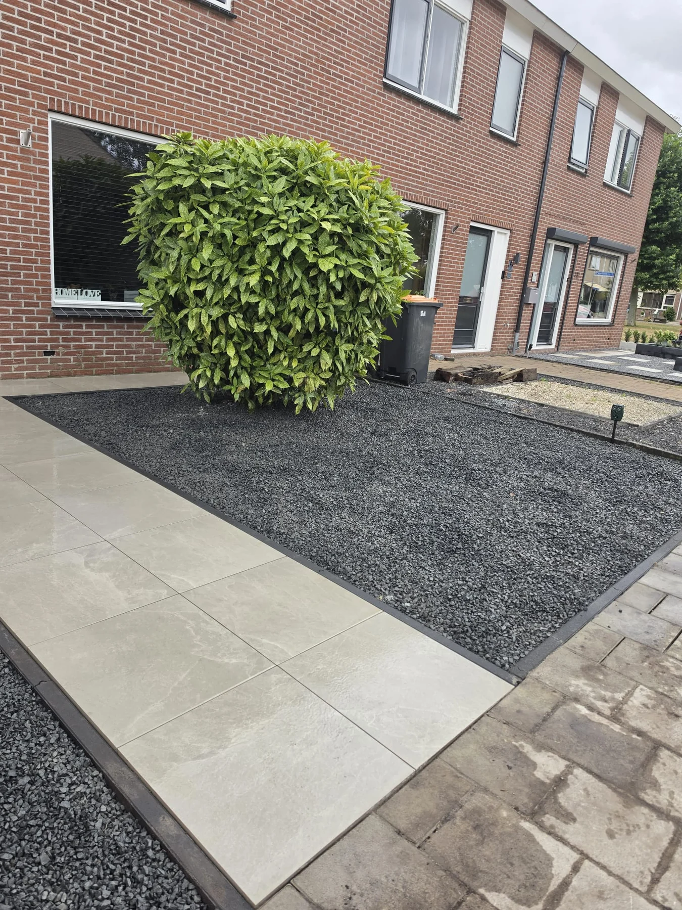 Voortuin met grootformaat tegels, siergrind en strakke randafwerking